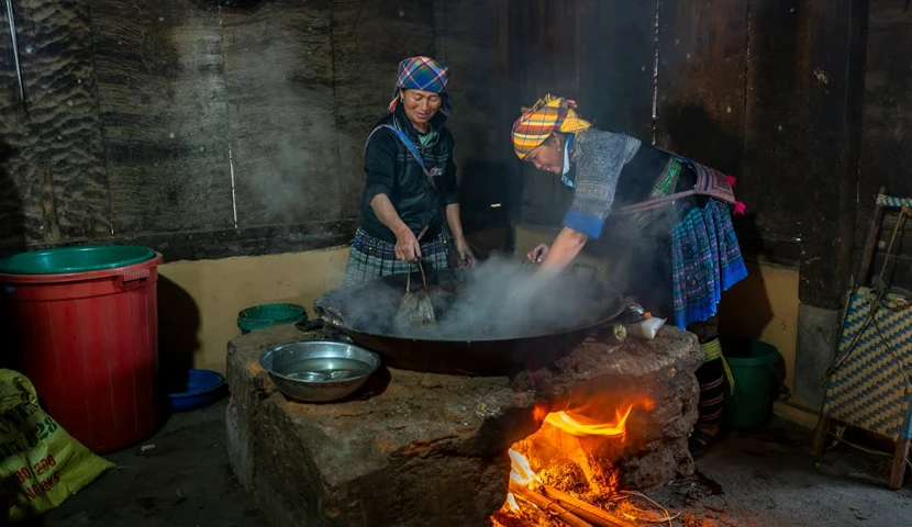 Donne Hmong di Sapa in abiti tradizionali mentre cucinano su un fuoco all’aperto