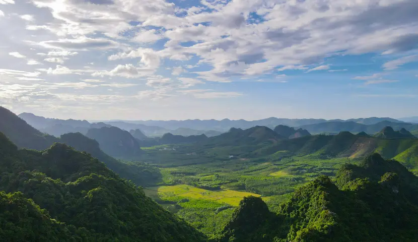 Lush green mountains under a cloudy blue sky