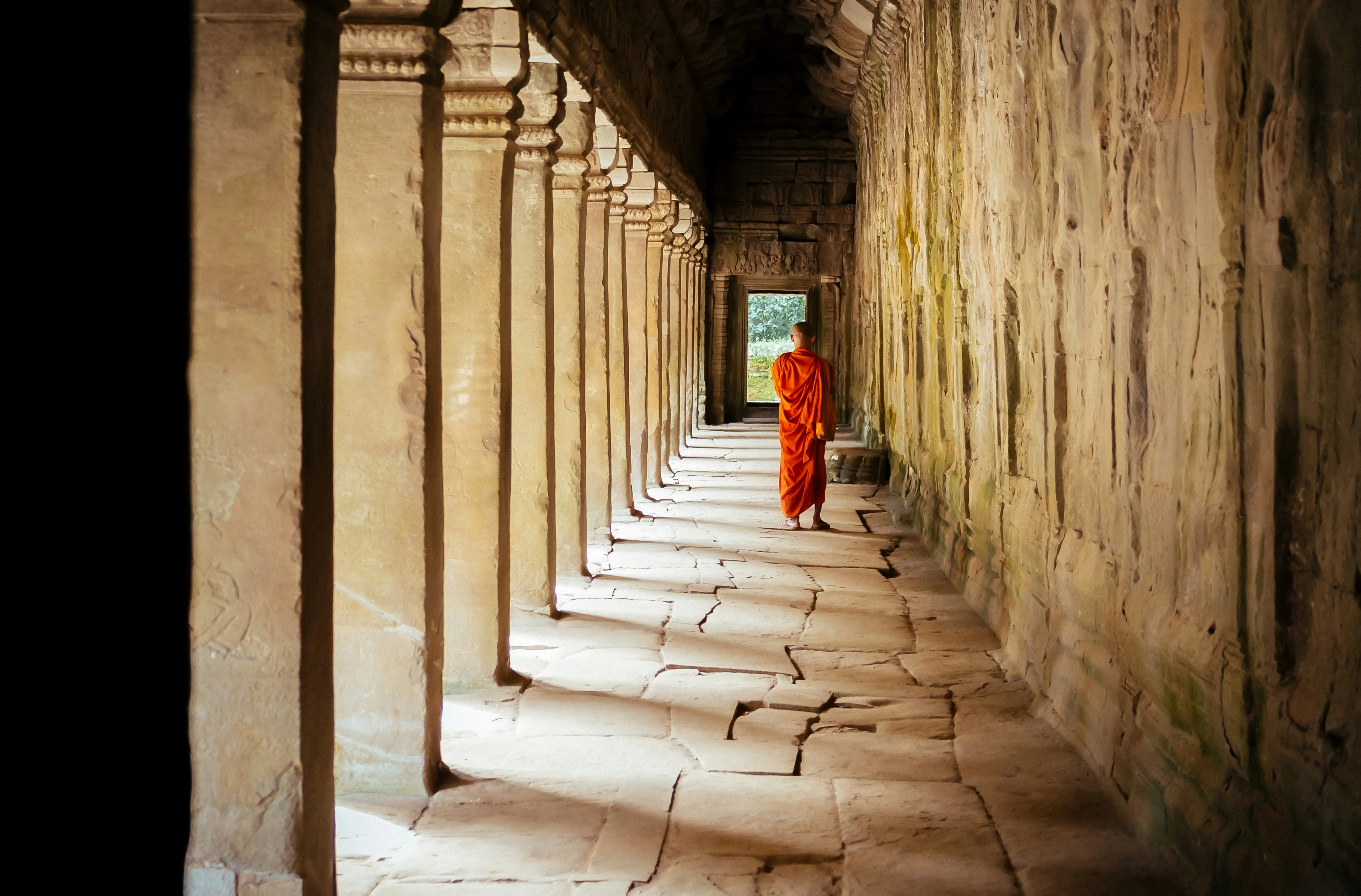 Selective focus photography of monk at corridor