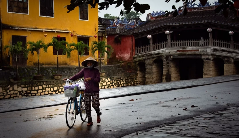 woman with bike passing the bridge in Hoi An